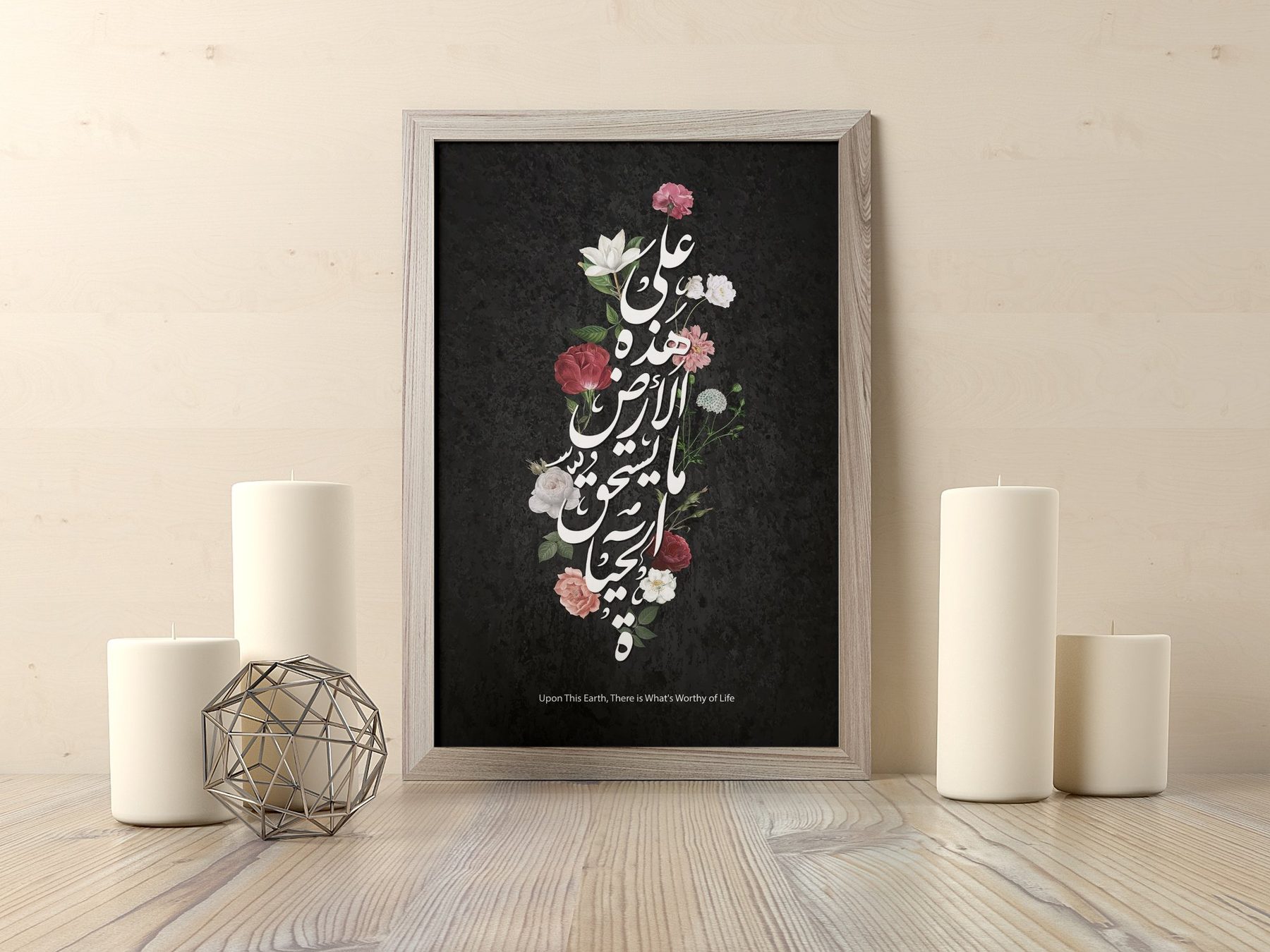 A framed Arabic calligraphy print with flowers on a dark ground, beside candles